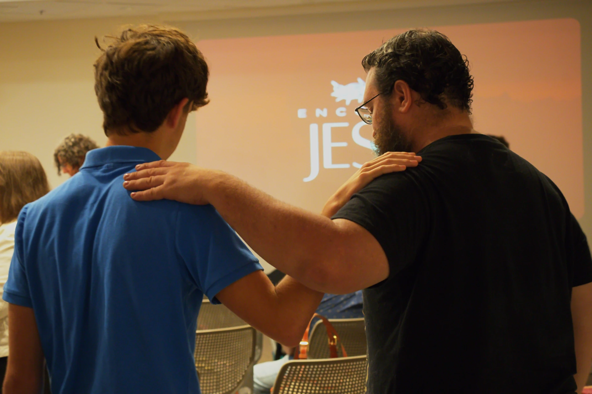 Group of two men praying for eachother.