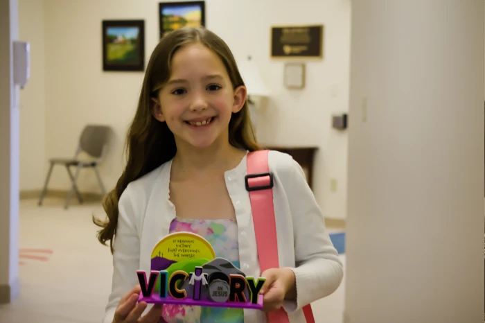 A girl holding up a victory craft they made during kids service.