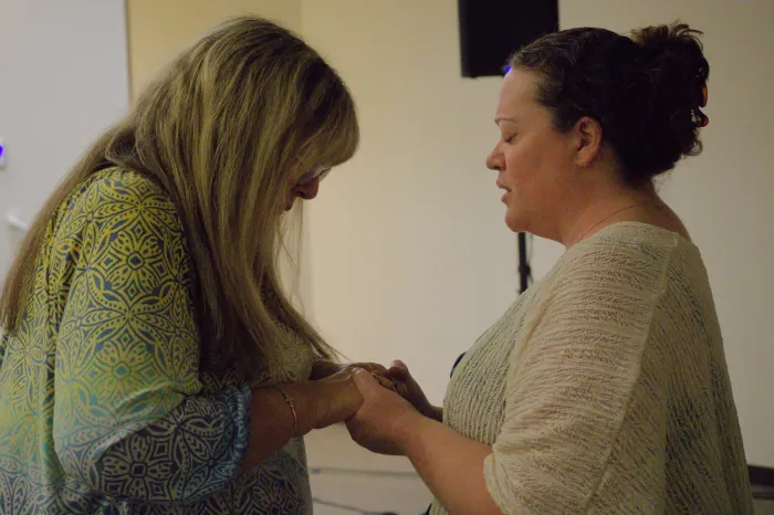 Two women praying over each other.
