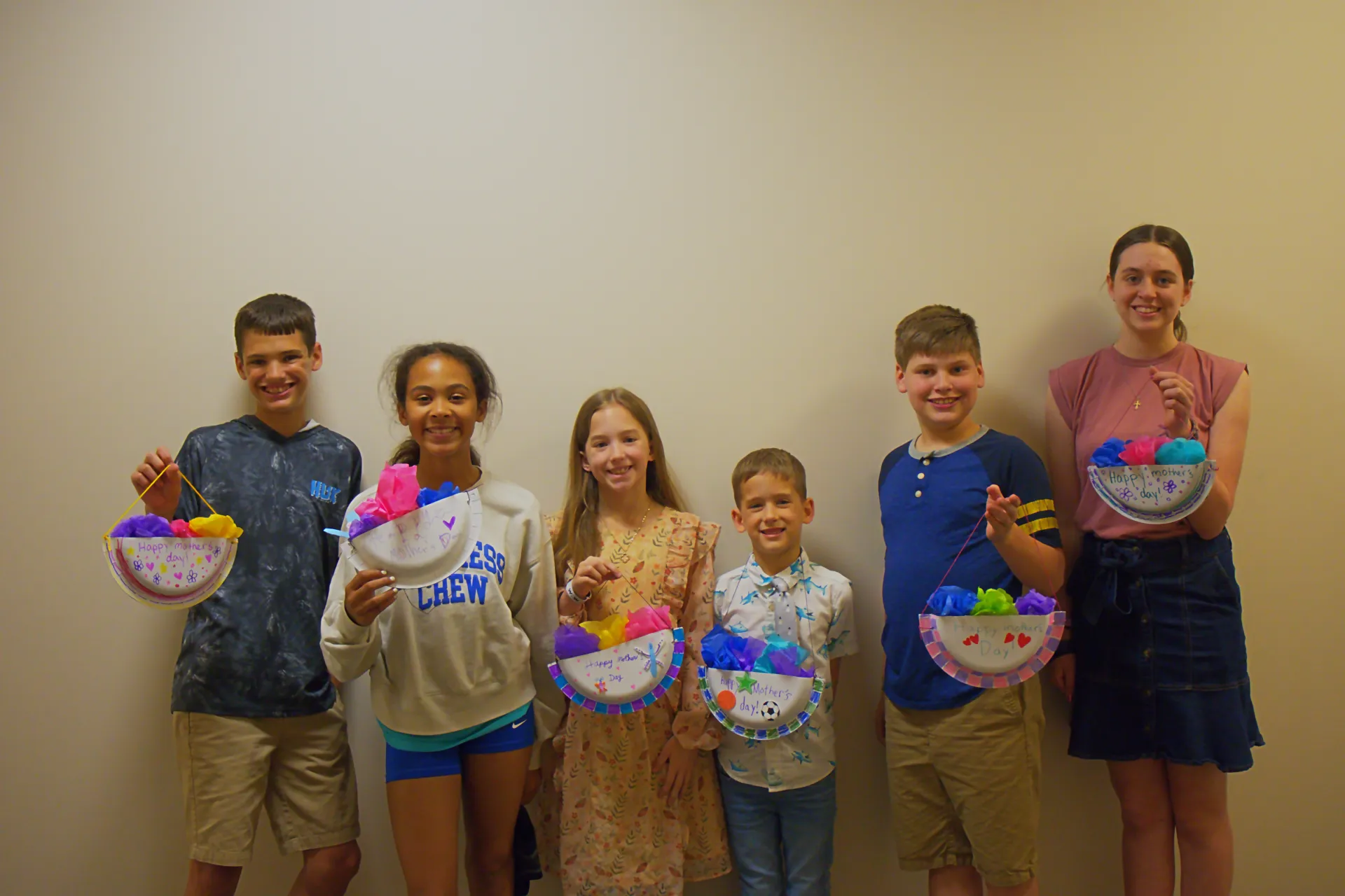 A kids group of six holding up crafts they made.